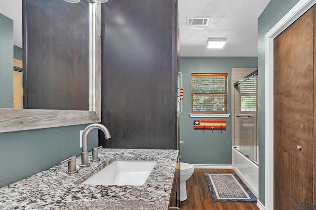 1907 Mary Jane Dr, Longview, TX 75601 - full bathroom with wood finished floors, vanity, a textured ceiling, and bath / shower combo with glass door