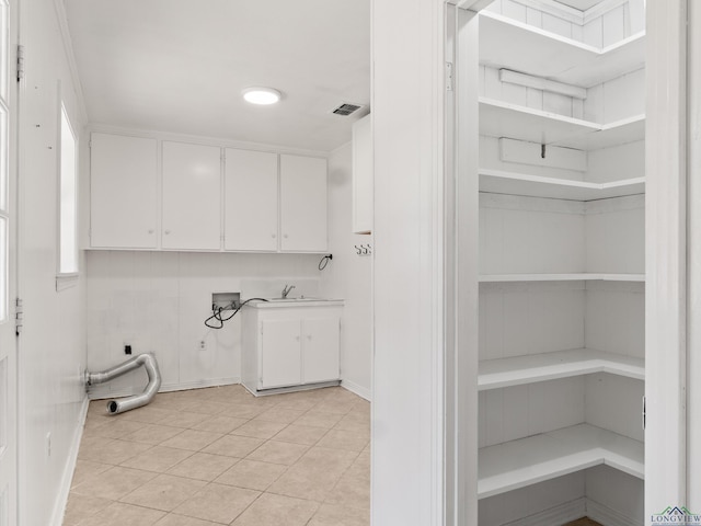 washroom featuring washer hookup, electric dryer hookup, light tile patterned floors, and cabinets