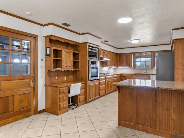 kitchen with ornamental molding, stainless steel appliances, sink, and dark stone countertops