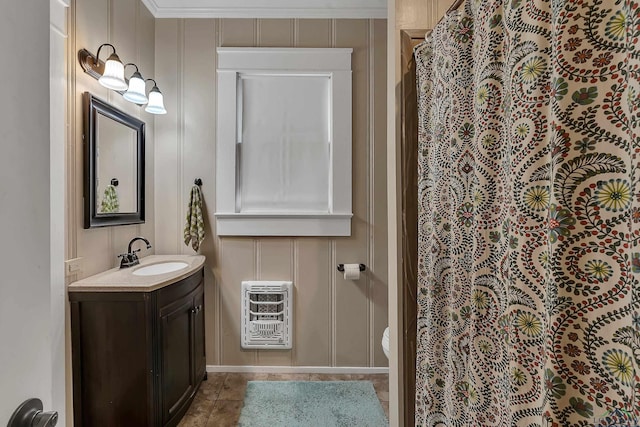 bathroom featuring tile patterned flooring, heating unit, vanity, ornamental molding, and toilet