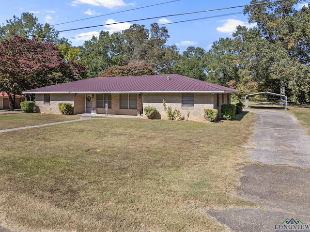 single story home with aphalt driveway, brick siding, a detached carport, metal roof, and a front lawn