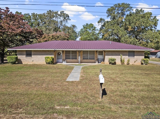 ranch-style home featuring metal roof, brick siding, and a front yard