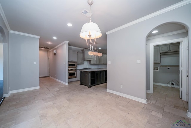 kitchen featuring a kitchen island, baseboards, tasteful backsplash, arched walkways, and appliances with stainless steel finishes