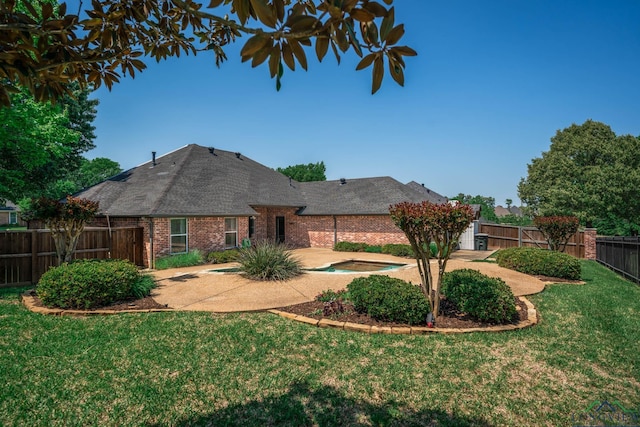 back of property with roof with shingles, brick siding, a fenced backyard, a patio area, and a lawn