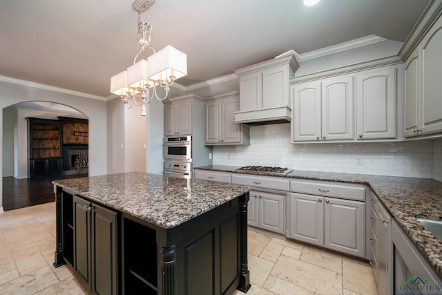 kitchen featuring stone tile floors, arched walkways, ornamental molding, and stainless steel gas stovetop