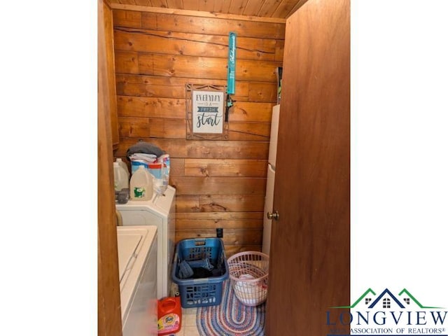 laundry area featuring wooden ceiling, washing machine and dryer, and wood walls