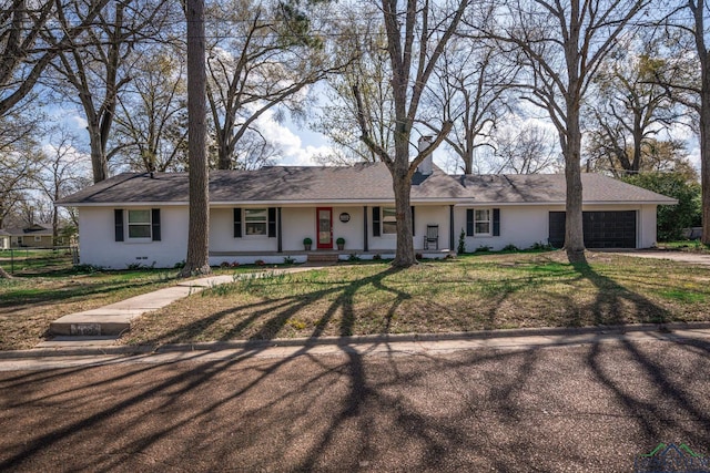 single story home with covered porch, a garage, and a front yard