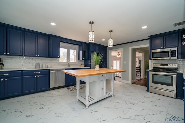 kitchen with appliances with stainless steel finishes, decorative light fixtures, sink, backsplash, and blue cabinetry