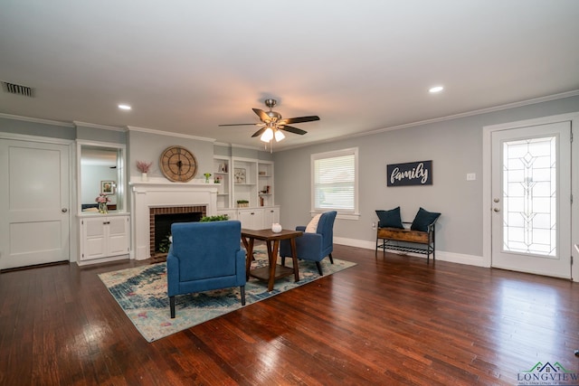 living room with ornamental molding, built in shelves, ceiling fan, a fireplace, and dark hardwood / wood-style floors