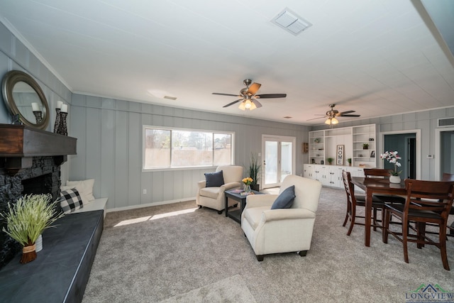 carpeted living room featuring built in shelves, ceiling fan, and ornamental molding