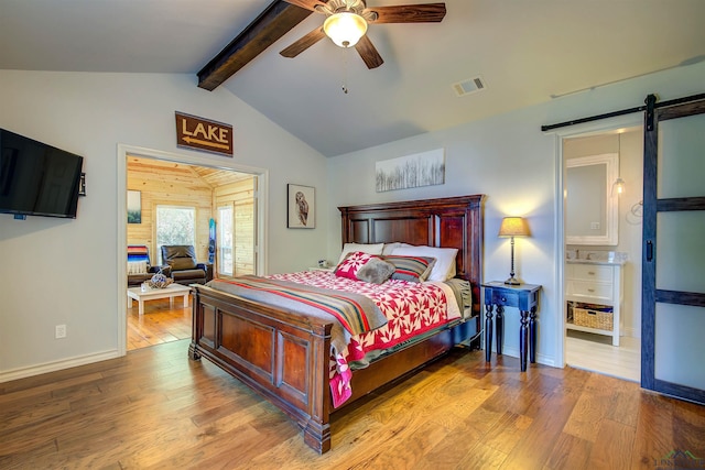bedroom with lofted ceiling with beams, wood finished floors, a barn door, visible vents, and baseboards