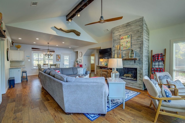 living area with lofted ceiling with beams, wood finished floors, visible vents, a fireplace, and a ceiling fan