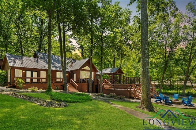 exterior space with a yard, a garage, stairway, a wooden deck, and a fire pit