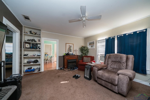 living room featuring cooling unit, built in shelves, carpet floors, and ceiling fan