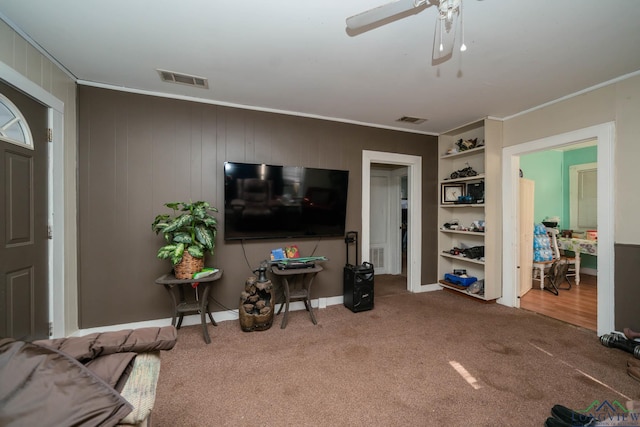 living room featuring crown molding, ceiling fan, and carpet floors