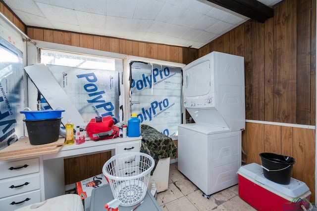 laundry room with stacked washer and clothes dryer and wood walls