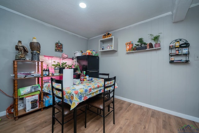 dining room featuring crown molding, baseboards, and wood finished floors