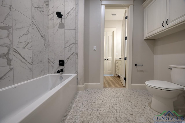 bathroom featuring tiled shower / bath combo and toilet