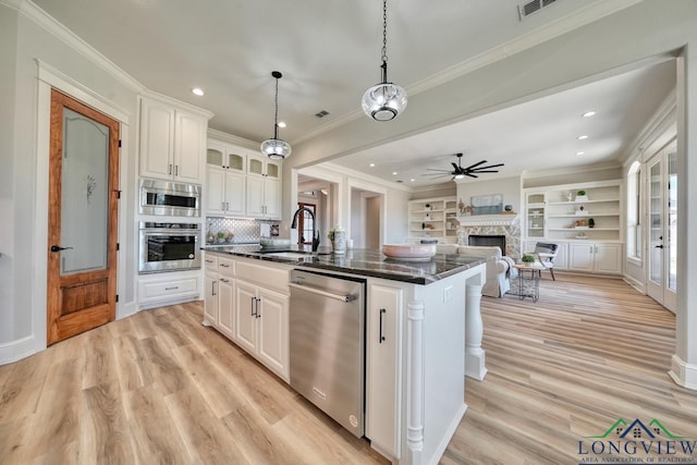 kitchen featuring white cabinetry, an island with sink, sink, hanging light fixtures, and stainless steel appliances