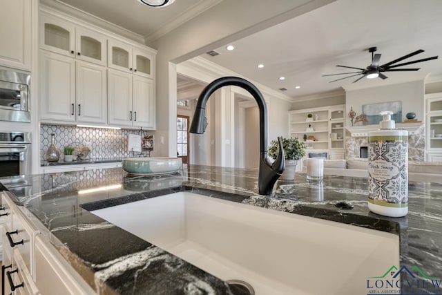 kitchen featuring sink, stainless steel appliances, ornamental molding, white cabinets, and dark stone counters