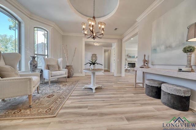 sitting room with a fireplace, ornamental molding, a chandelier, and light wood-type flooring