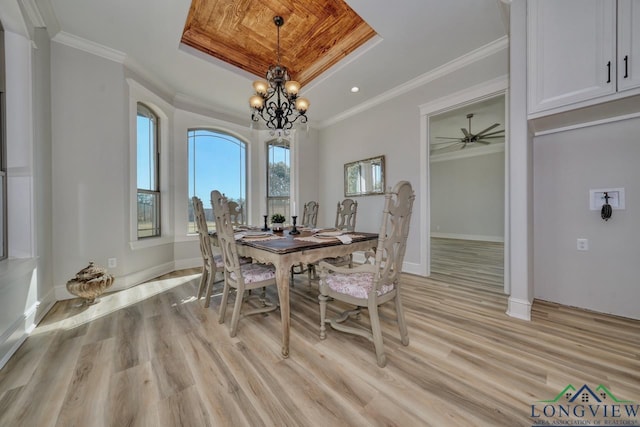 dining space featuring a raised ceiling, crown molding, a notable chandelier, and light hardwood / wood-style flooring