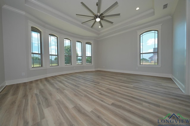 unfurnished room with ornamental molding, ceiling fan, light hardwood / wood-style floors, and a tray ceiling