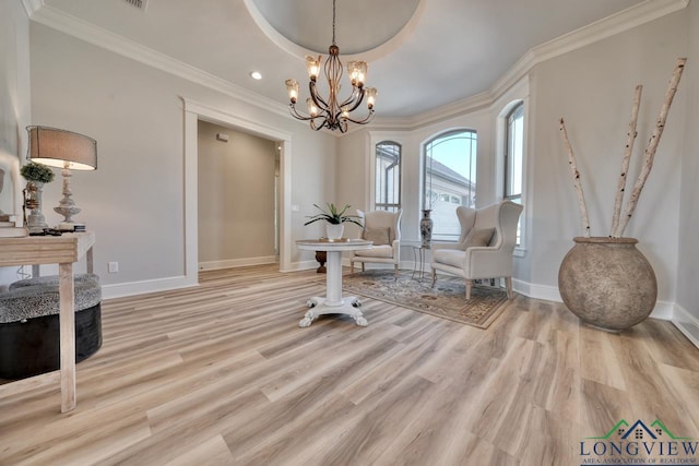 sitting room with an inviting chandelier, crown molding, light hardwood / wood-style floors, and a tray ceiling