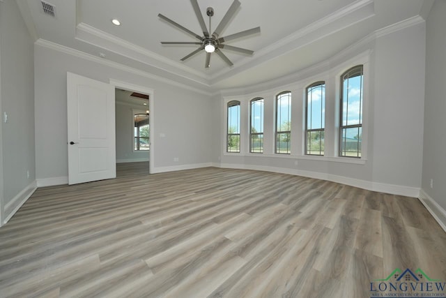 unfurnished room with ornamental molding, ceiling fan, light wood-type flooring, and a tray ceiling