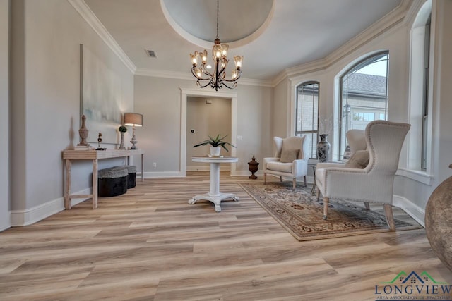 living area featuring a raised ceiling, ornamental molding, a chandelier, and light hardwood / wood-style floors