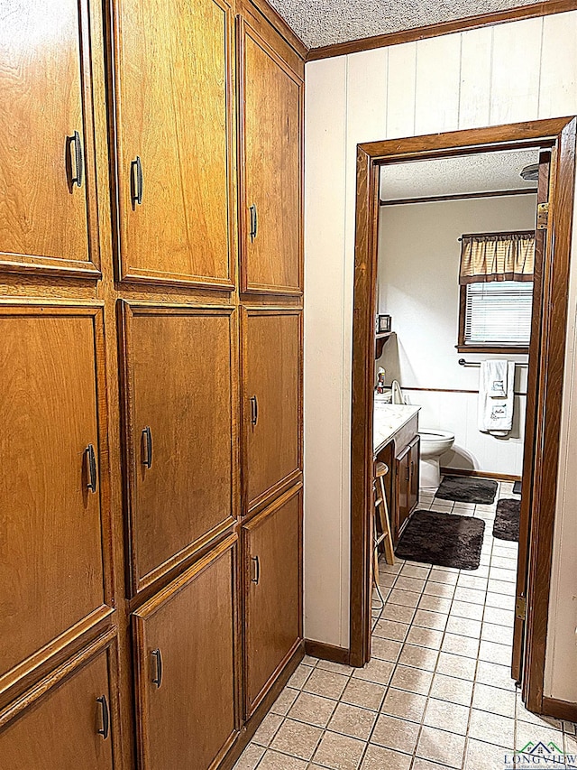 906 Misty Ln, Atlanta, TX 75551 - bathroom featuring tile patterned floors, vanity, a textured ceiling, wood walls, and ornamental molding