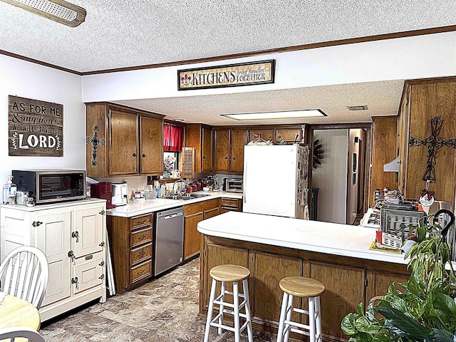 906 Misty Ln, Atlanta, TX 75551 - kitchen featuring stainless steel dishwasher, a textured ceiling, freestanding refrigerator, a peninsula, and light countertops
