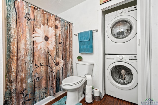 bathroom featuring stacked washer and dryer, hardwood / wood-style floors, and toilet