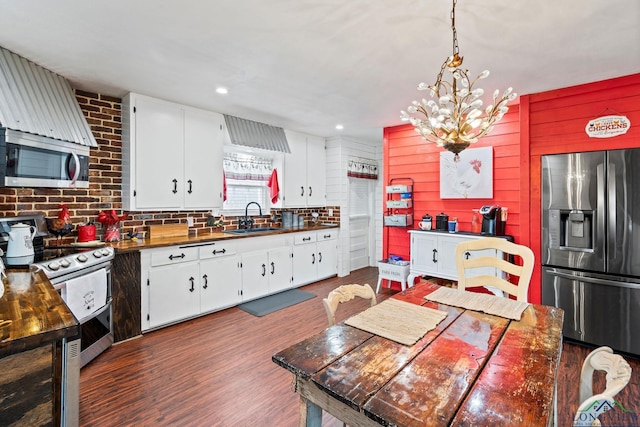 kitchen with white cabinetry, stainless steel appliances, sink, and pendant lighting