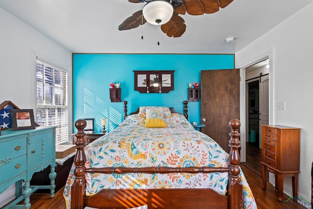 bedroom featuring dark hardwood / wood-style flooring, a barn door, and ceiling fan