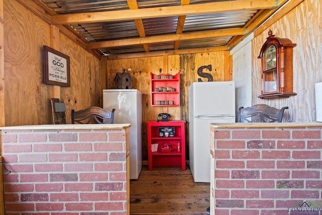 kitchen featuring wood-type flooring, white fridge, and wood walls