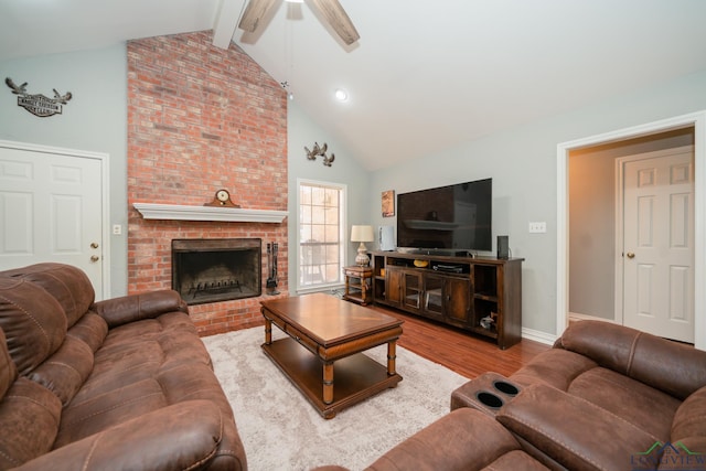 living room with a brick fireplace, ceiling fan, beam ceiling, high vaulted ceiling, and light hardwood / wood-style floors