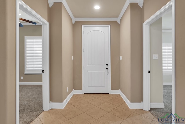 foyer featuring crown molding, light tile patterned flooring, baseboards, and light carpet