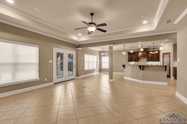 unfurnished living room featuring a tray ceiling, light tile patterned floors, ceiling fan with notable chandelier, and visible vents