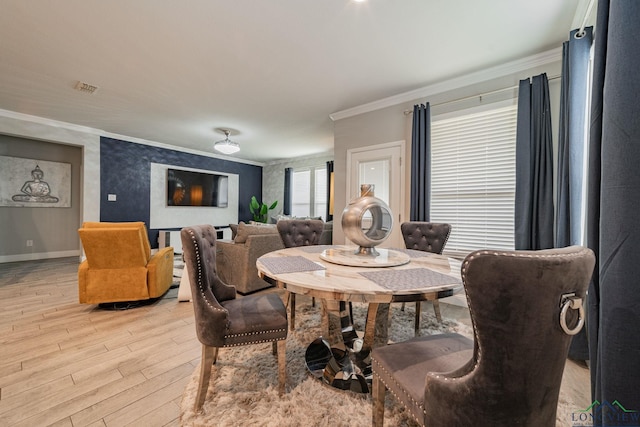 dining space featuring ornamental molding and light hardwood / wood-style flooring