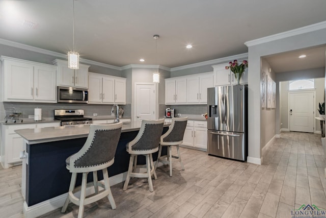 kitchen with white cabinetry, hanging light fixtures, an island with sink, decorative backsplash, and appliances with stainless steel finishes