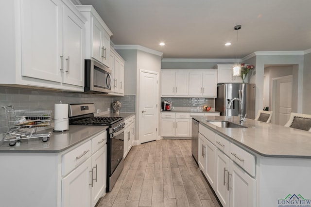 kitchen featuring white cabinets, appliances with stainless steel finishes, pendant lighting, and sink