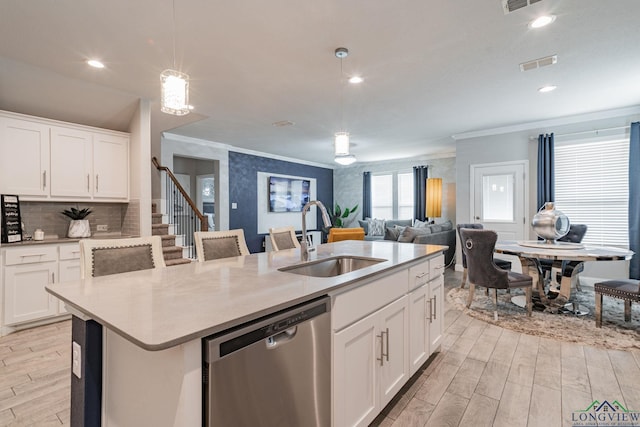 kitchen featuring dishwasher, sink, hanging light fixtures, a kitchen island with sink, and white cabinets