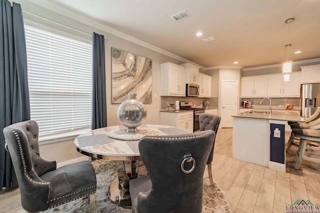 dining room featuring light hardwood / wood-style floors, crown molding, and sink