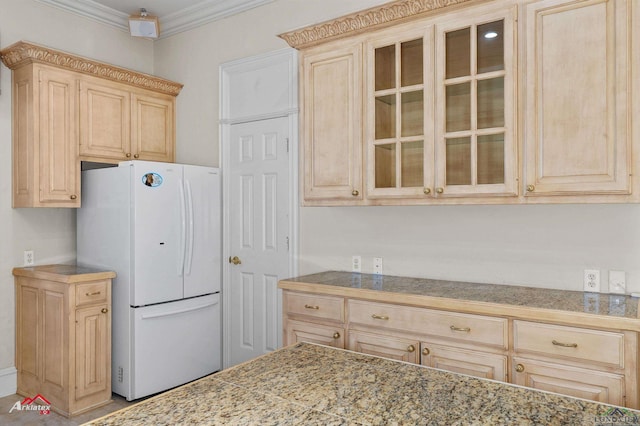 kitchen featuring white refrigerator, crown molding, and light brown cabinetry