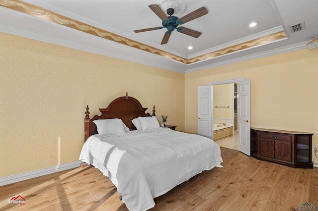 bedroom featuring ceiling fan, a raised ceiling, light hardwood / wood-style flooring, ensuite bathroom, and ornamental molding