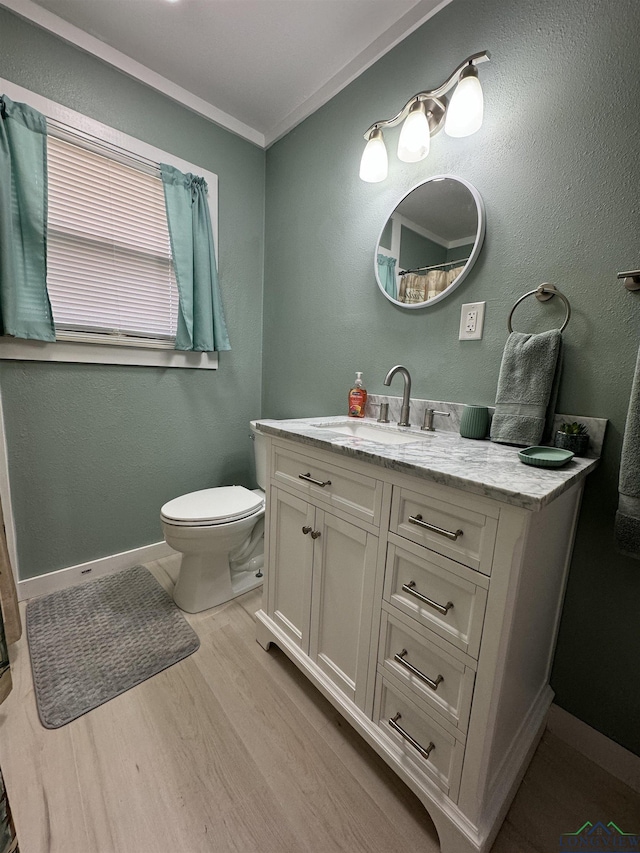 bathroom with hardwood / wood-style flooring, ornamental molding, vanity, and toilet