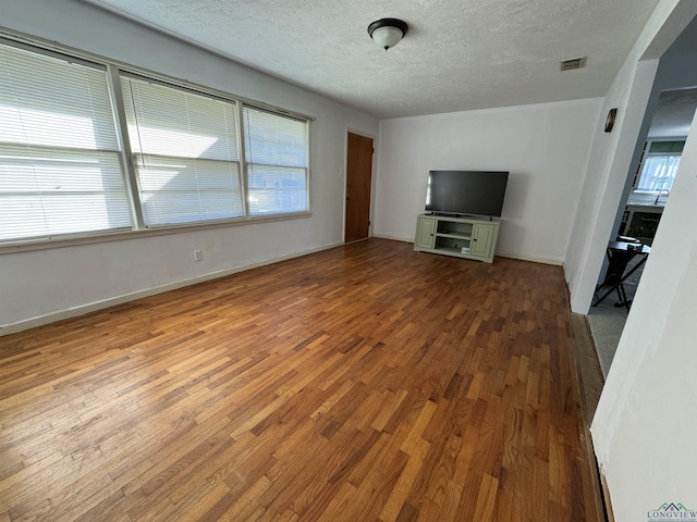 unfurnished living room featuring wood-type flooring and a textured ceiling