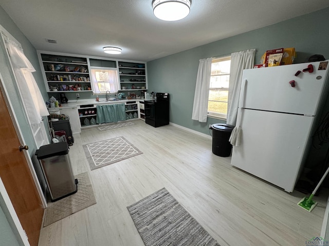 kitchen with white fridge, sink, and light wood-type flooring