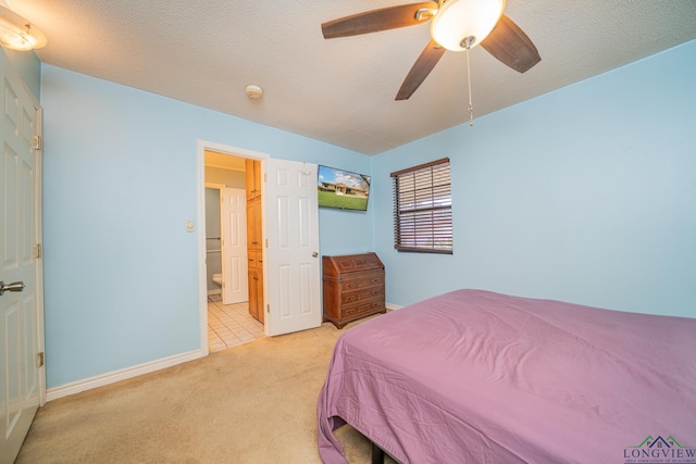 bedroom with ceiling fan, light colored carpet, ensuite bathroom, and a textured ceiling